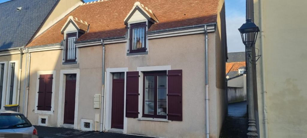 a building with purple doors and a brown roof at Maison DEOLS centre pour 1 a 2 personnes in Déols