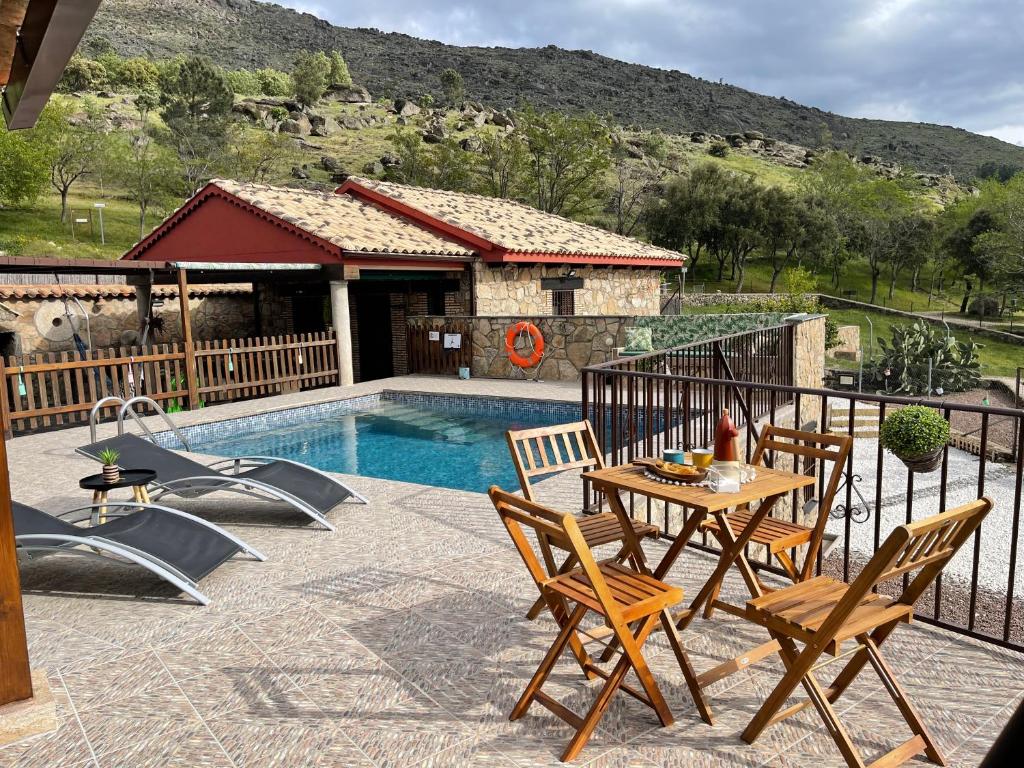 um pátio com uma mesa e cadeiras ao lado de uma piscina em Casa Apartamento Rural U Penafrol em Eljas