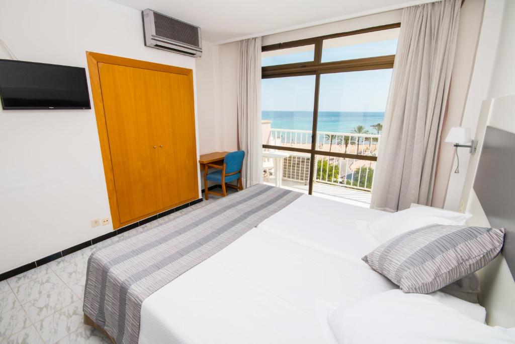 a bedroom with a bed and a balcony with the ocean at Hotel Amic Miraflores in Can Pastilla