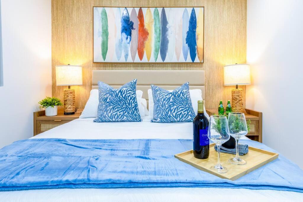 1 cama con sábanas azules y 2 botellas y vasos en Serenity Lodge II Condo en Miami