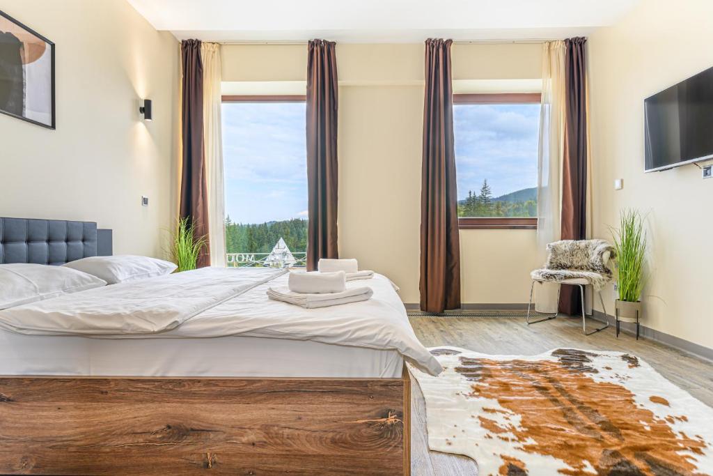 - une chambre avec un grand lit et une grande fenêtre dans l'établissement B41 Apartment Poiana Brasov, à Poiana Brasov