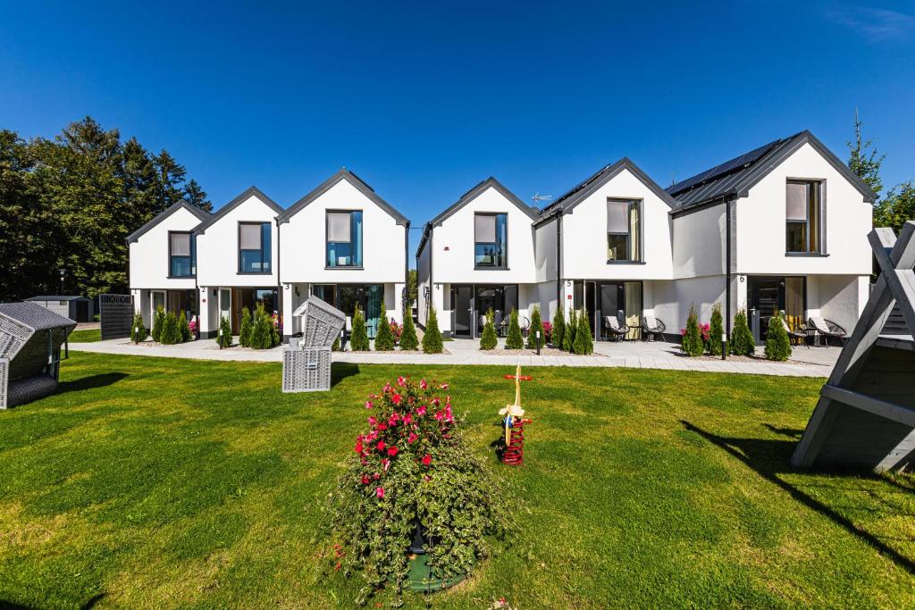 a row of white houses with flowers in a yard w obiekcie Ferienhäuser Natureck - Zakątek Natury w Rewalu