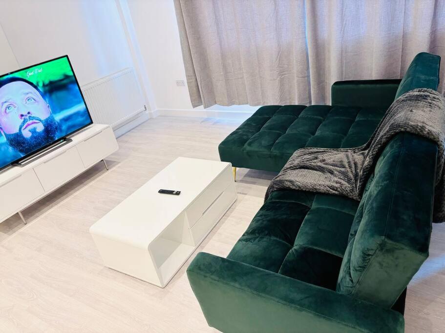 a living room with a green couch and a tv at Ace Apartments in Barking