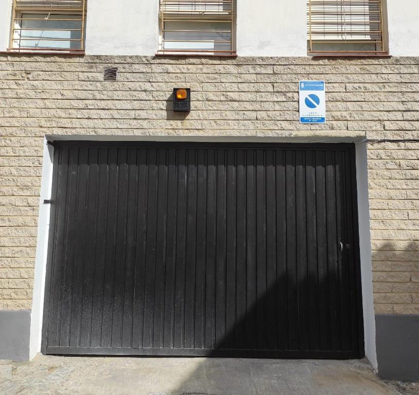 a black garage door on a brick building at Loft Xera - parking privado in Jerez de la Frontera