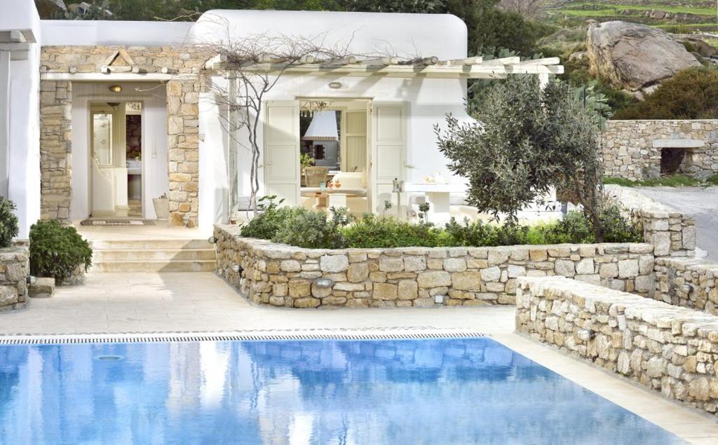 a house with a swimming pool and a stone wall at Villa Mon Rêve "5-minute walk beach, restaurants, supermarket" in Mýkonos City