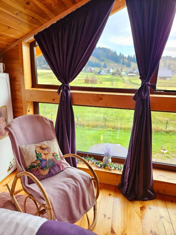 ein Schlafzimmer mit einem Stuhl vor einem Fenster in der Unterkunft La Căsuță in Vatra Dornei