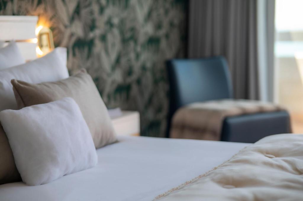 a hotel room with a bed with pillows and a chair at Arribas Sintra Hotel in Sintra