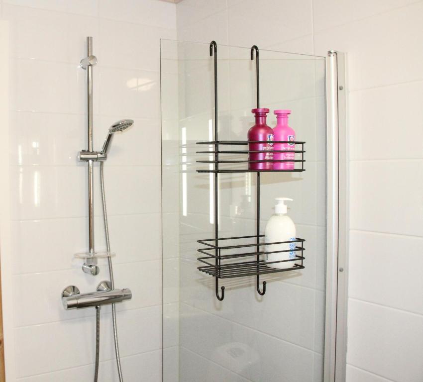een badkamer met een douche en roze flessen op een plank bij Apartment with Sauna in the heart of Rovaniemi in Rovaniemi