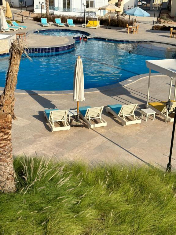 uma piscina com cadeiras e guarda-sóis e uma mesa e uma piscina em Babushka Boutique Hotel-Dahab em Dahab