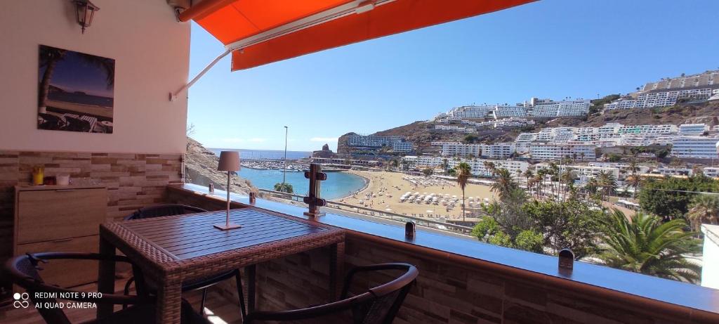 un tavolo e sedie su un balcone con vista sulla spiaggia di MGT - Appartamento sulla Spiaggia con terrazza romantica a Puerto Rico de Gran Canaria