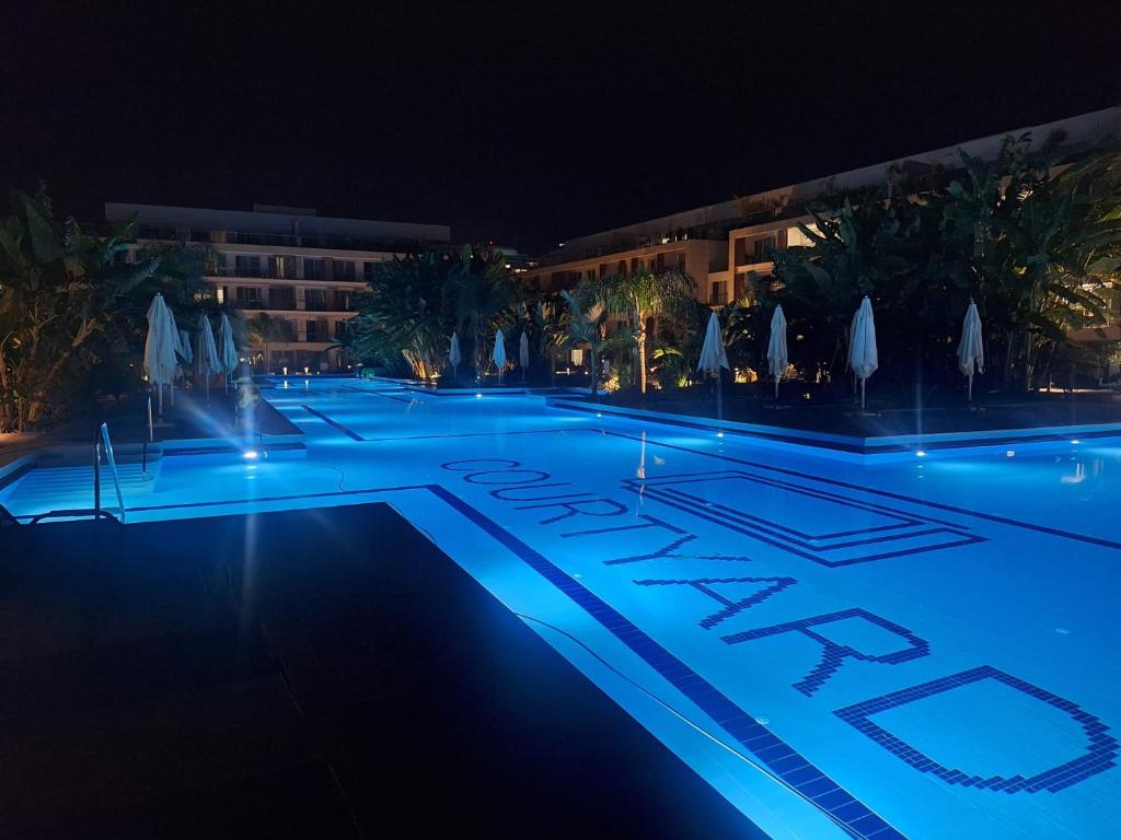 a swimming pool at night with blue lights at Courtyard Long Beach Apartment in Iskele