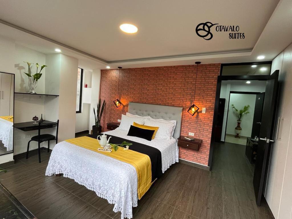 sypialnia z łóżkiem i ceglaną ścianą w obiekcie Otavalo Suites w mieście Otavalo