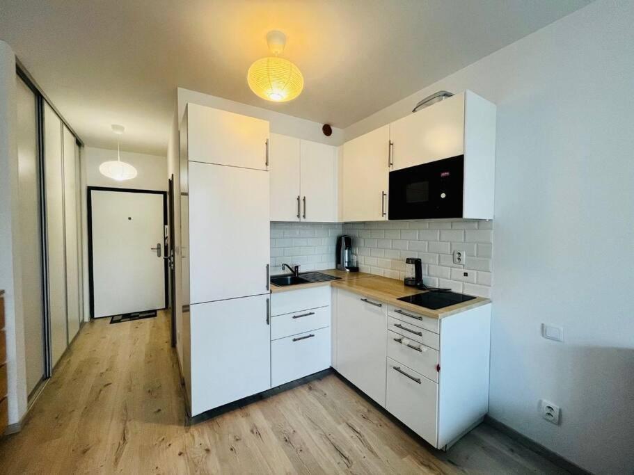 a kitchen with white cabinets and a wooden floor at Apartmán v Bratislave in Bratislava