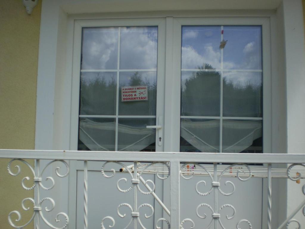 Un balcón con una puerta con un cartel. en Adikati Lak en Bük