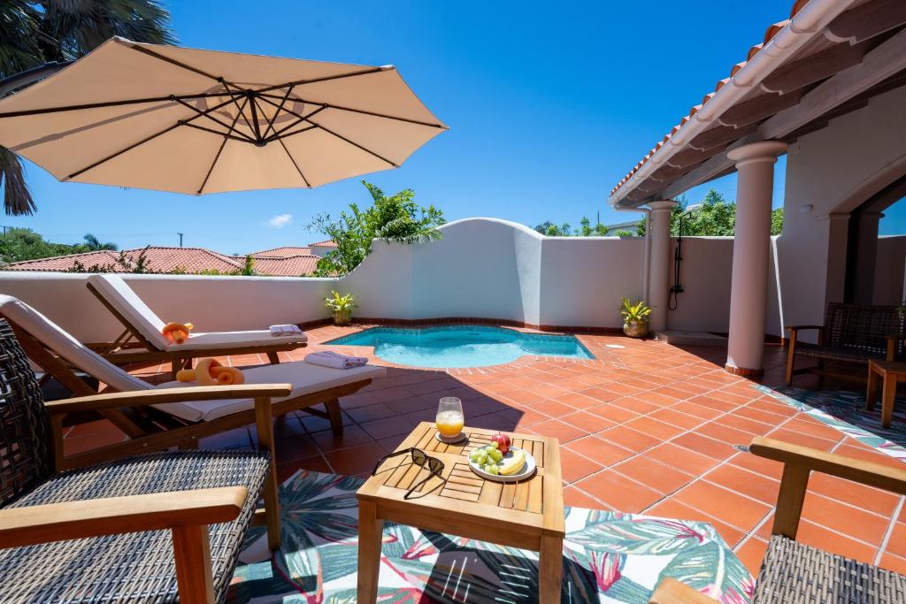 a patio with an umbrella and a pool at Villa III in Lance aux Épines