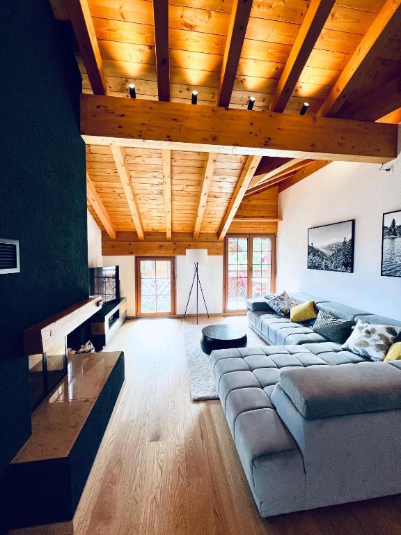 un soggiorno con un grande divano e soffitti in legno di Alpenresidenz - CharmingStay a Flumserberg