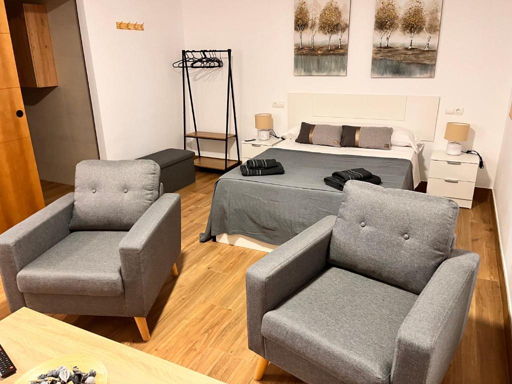 salon z łóżkiem i 2 krzesłami w obiekcie Apartamentos El PELIGRO 2 LAHIVE w mieście Archidona
