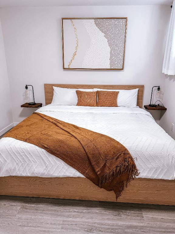een slaapkamer met een bed met een bruine deken erop bij Brand New 2 Bedroom Basement Suite in Calgary in Calgary