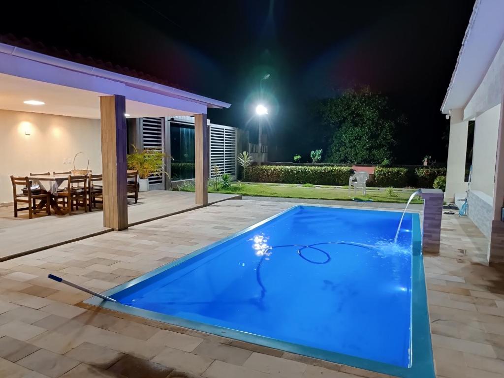 ein Pool im Garten mit einem Tisch in der Nacht in der Unterkunft casa ampla com PISCINA e área verde em São José ao lado de Maragogi in São José da Coroa Grande