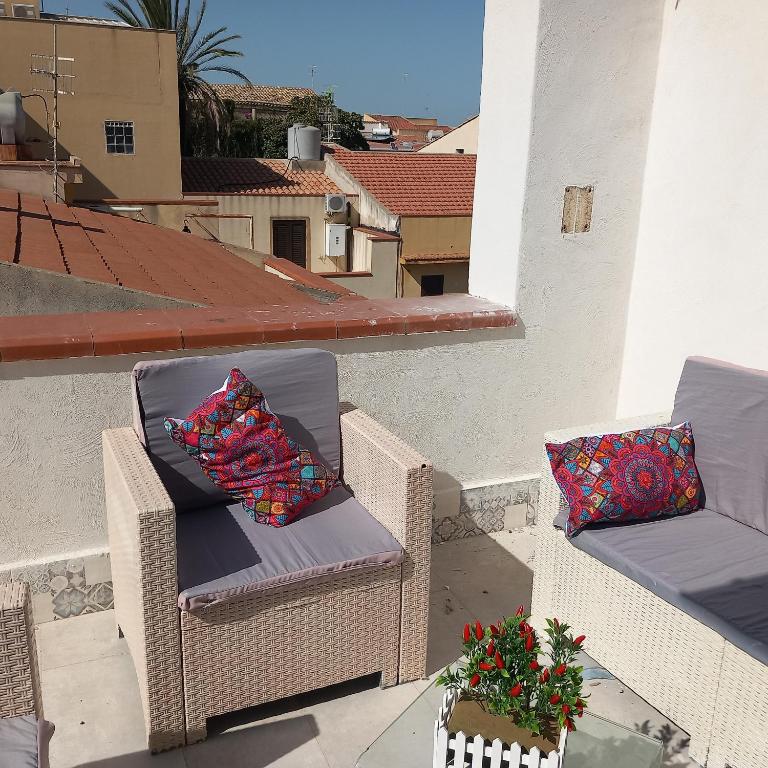 2 rieten stoelen op een balkon met een kussen bij BBWine Apartment 2 in Menfi