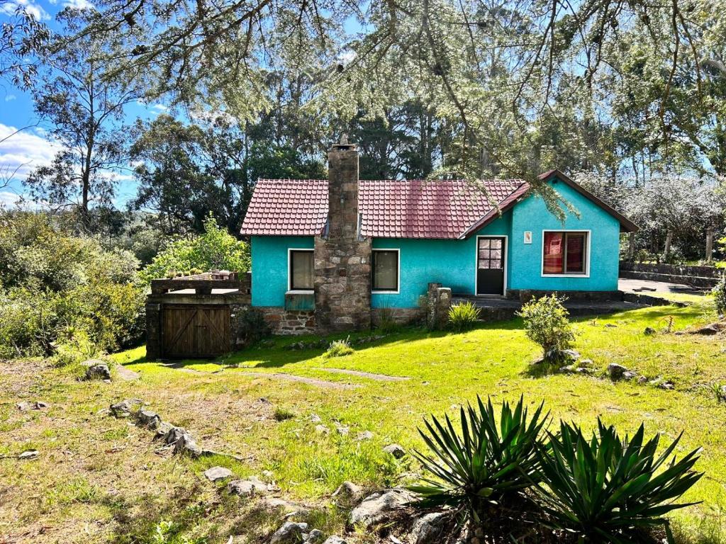 uma casa azul com um telhado vermelho num jardim verde em El rancho - Espaciosa Casa para 7 en un Oasis de Tranquilidad em Villa Serrana