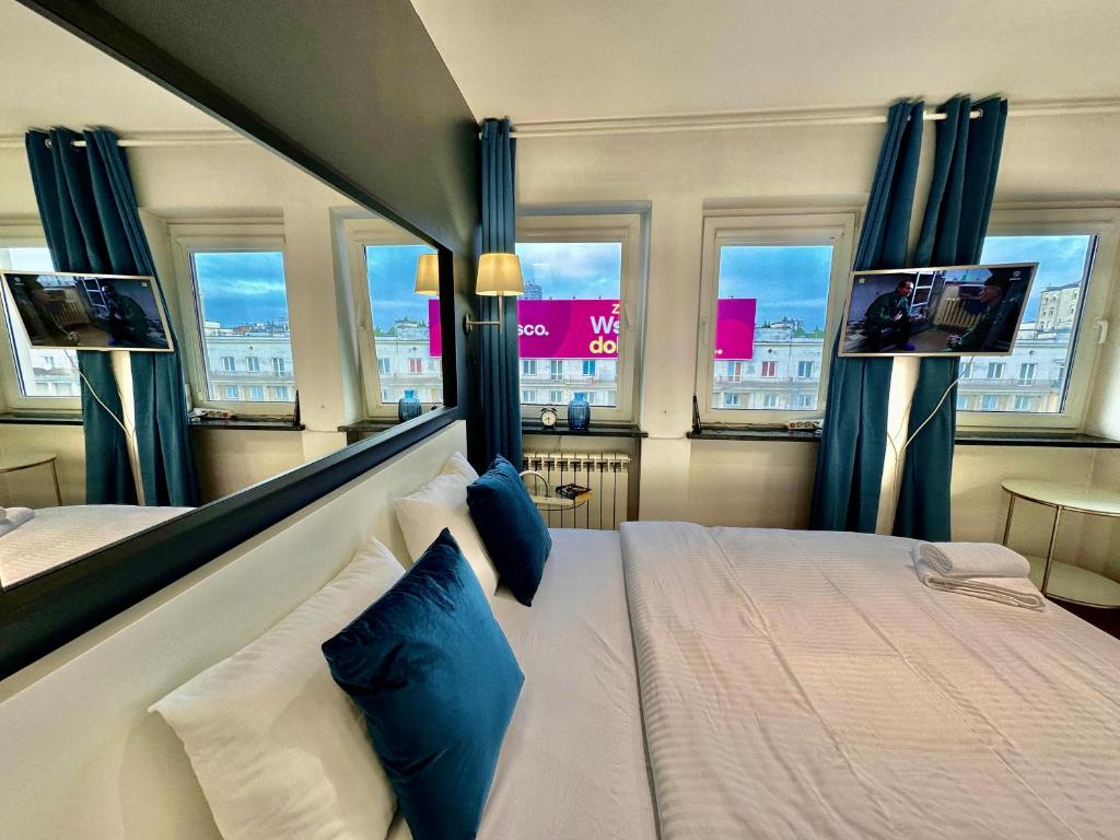 um quarto com uma cama com cortinas azuis e 2 televisões em FORUM 3 metro fast WiFi 400 Mbs TV HBO Disney+ em Varsóvia