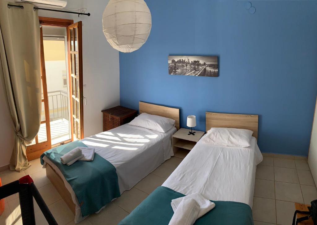 La Bandolaise à Perdika في بيرديكا: سريرين في غرفة ذات جدار أزرق
