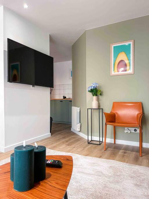 un salon avec une télévision à écran plat et une chaise dans l'établissement La Vie est Belle à Montreuil Wi-Fi & Métro 9 Parking gratuit, à Montreuil