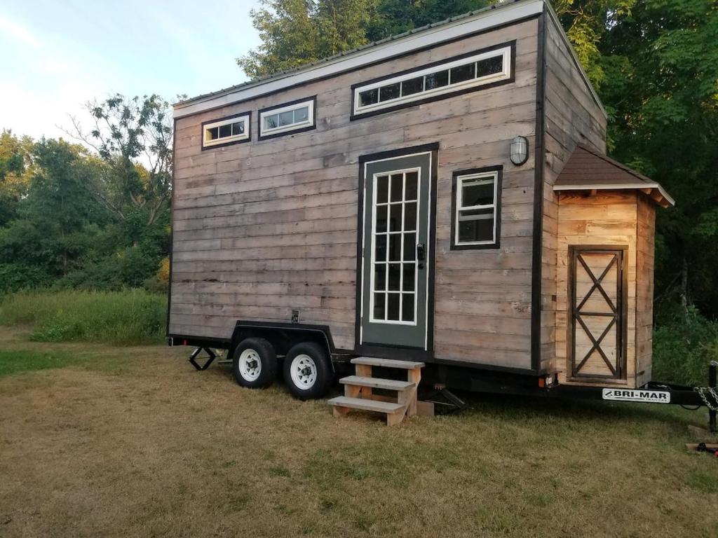 una casetta su una roulotte in un campo di Adirondack Country Living Tiny House Village a Canton