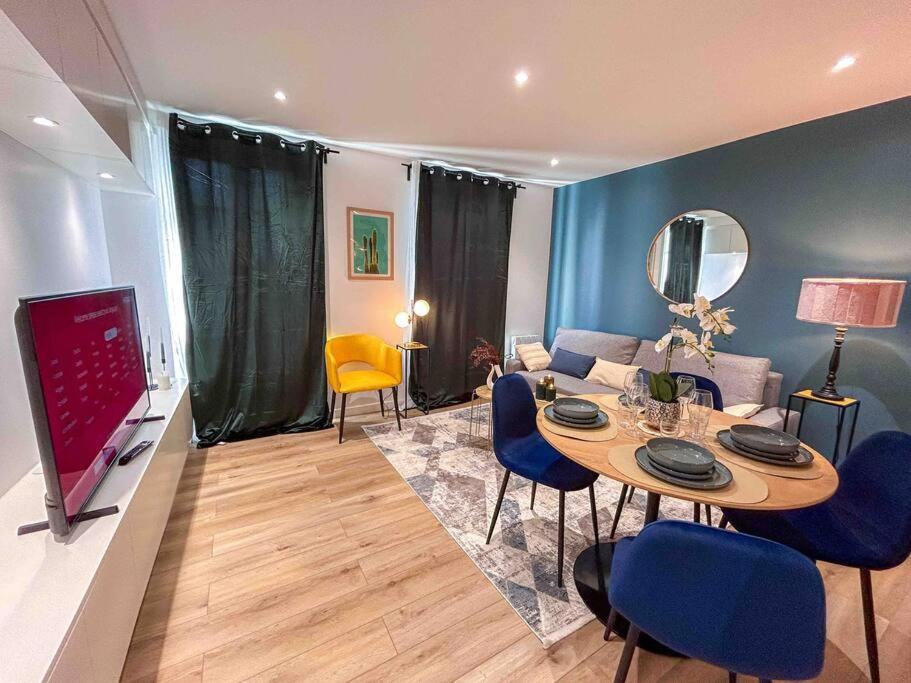 ein Wohnzimmer mit einem Tisch und blauen Stühlen in der Unterkunft L‘Éden au Porte de Paris Metro 9 in Montreuil