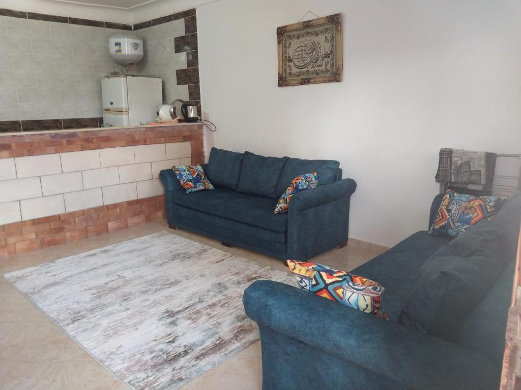un salon avec deux canapés bleus et une cuisine dans l'établissement Beachside Chalet ,Sidi kerir, à Abû Zeira