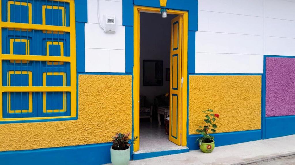 a colorful building with a yellow door and windows at Casa de huéspedes la Casona. in Medellín