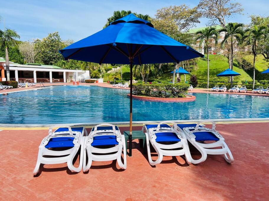 3 sillas y una sombrilla frente a una piscina en 3BR/3.5BA Golf & Beach Villa, en Río Hato