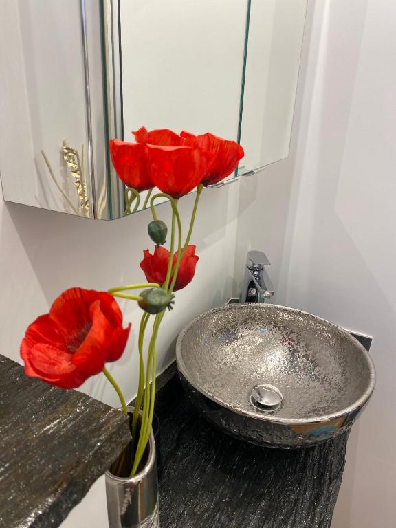 two red roses in a vase next to a sink at Paris-Zénith-bienvenue-terrasse-Netflix in Pantin