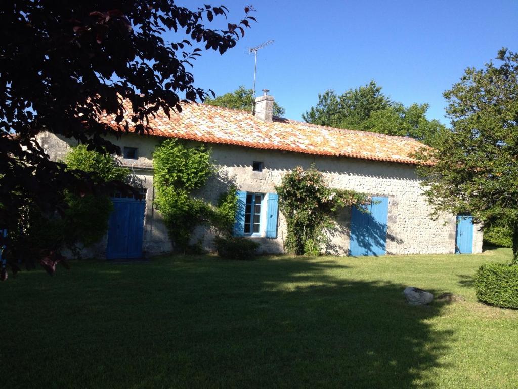an old stone house with blue doors and a yard at charme de l'ancien au coeur de la vallée sud charentaise in Bardenac
