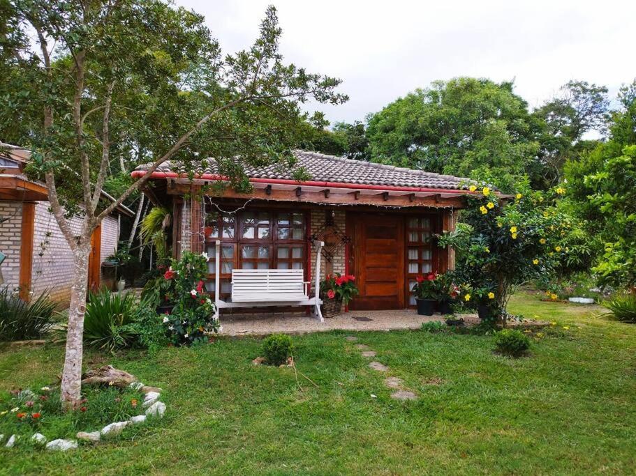 ein kleines Haus mit einer Bank im Hof in der Unterkunft Sitio com jaccuzi, fogão a lenha in Vitória da Conquista