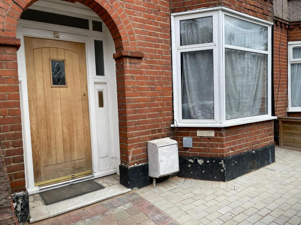 a brick building with a wooden door and two windows at Amazing Studio Room 3 - Chingford/NE London in Woodford