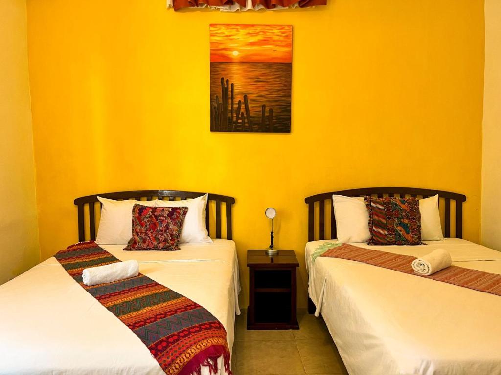 two beds in a room with yellow walls at Balamku Hotel Petit in Campeche