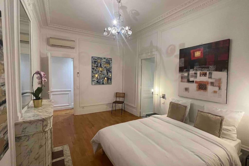 a bedroom with a large white bed and a chandelier at Splendid Eiffel Tower & La Seine - 8 Beds in Paris