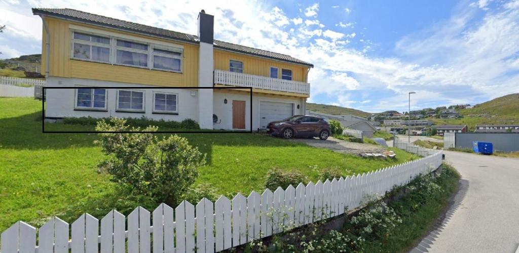 a yellow and white house with a white picket fence at Topview in Hammerfest