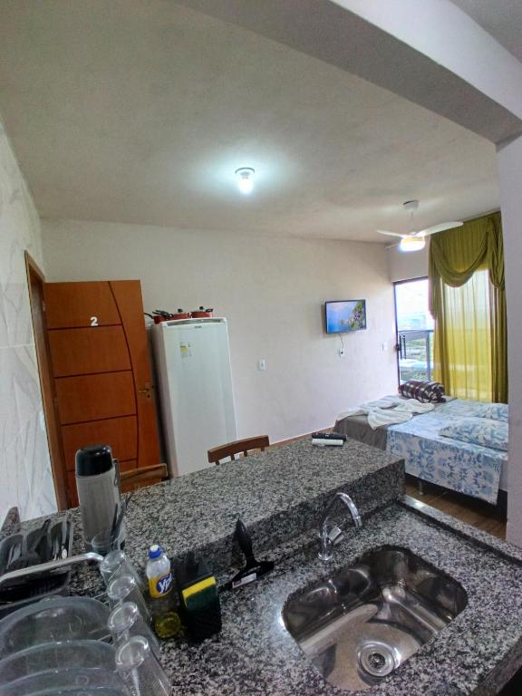 a kitchen with a sink and a room with a bed at Flat 02 com Varanda - Avenida Hospedagem in São Thomé das Letras