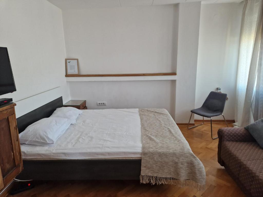 a bedroom with a bed and a chair and a television at Blue New Yorker in Niš