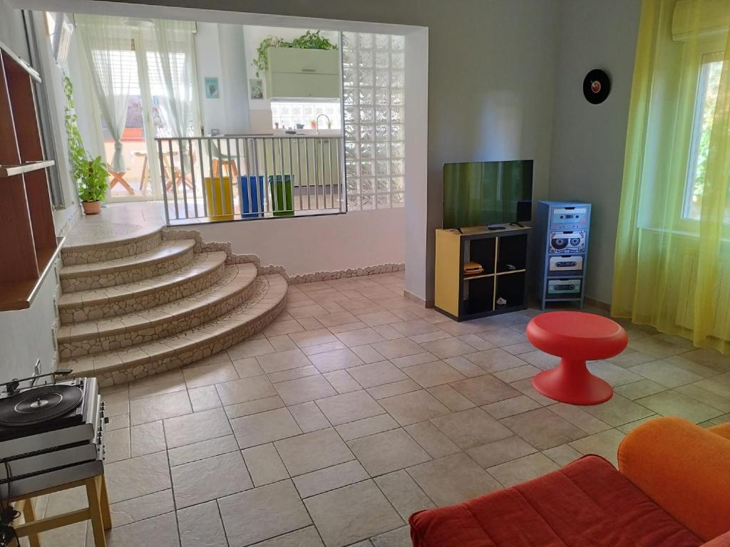 un soggiorno con scale e uno sgabello rosso di Appartamento Fronte Mare - parcheggio privato a Pescara