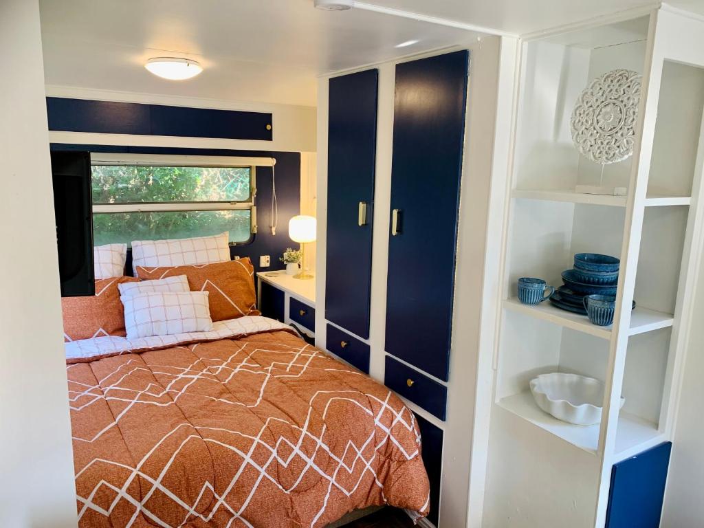 a bedroom with a bed and a window and shelves at Mornington Peninsula Retro Caravans in Rye