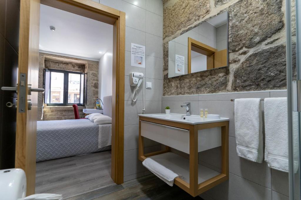 uma casa de banho com um lavatrio e uma cama num quarto em ALOJAMENTO GIRASSOL - Guest House - Quarto com casa de banho privativa em Castelo Branco