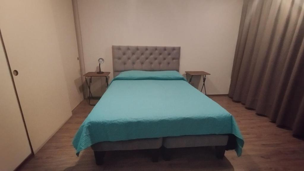 Alojamiento frente a Turbus في سانتياغو: غرفة نوم بسرير كبير مع بطانية زرقاء