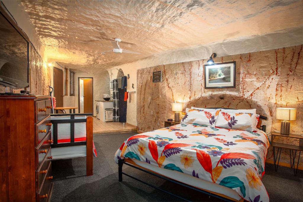 um quarto com uma cama e uma parede de pedra em Dinky Di's Dugout em Coober Pedy