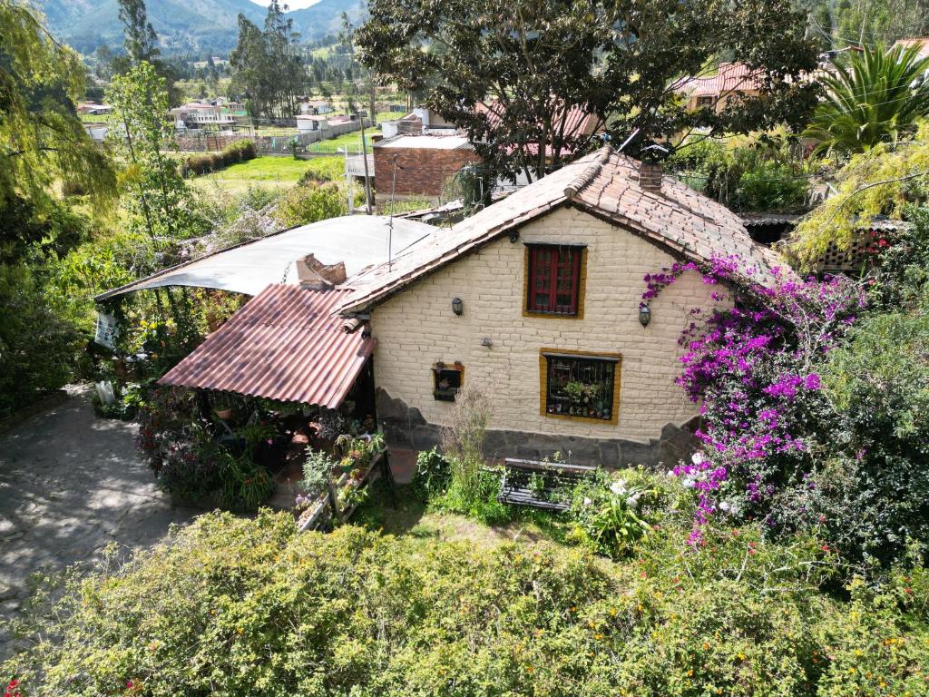 a small house with a red roof and some flowers at Libélula Cabaña- Alojamiento rural in Duitama