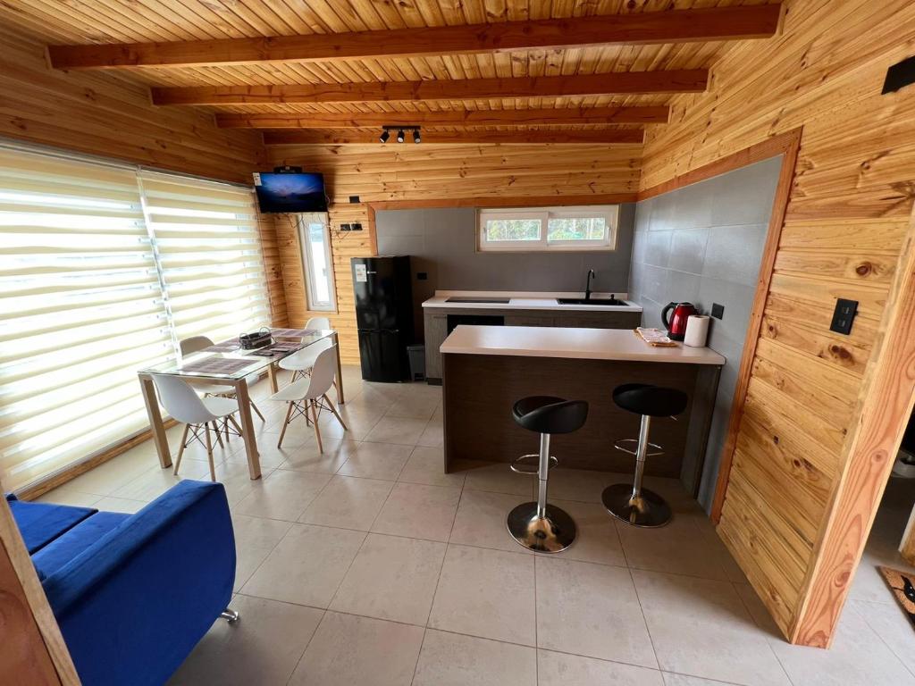 a kitchen with a counter and a table and chairs at Cabañas Santa Elena in Pelluhue