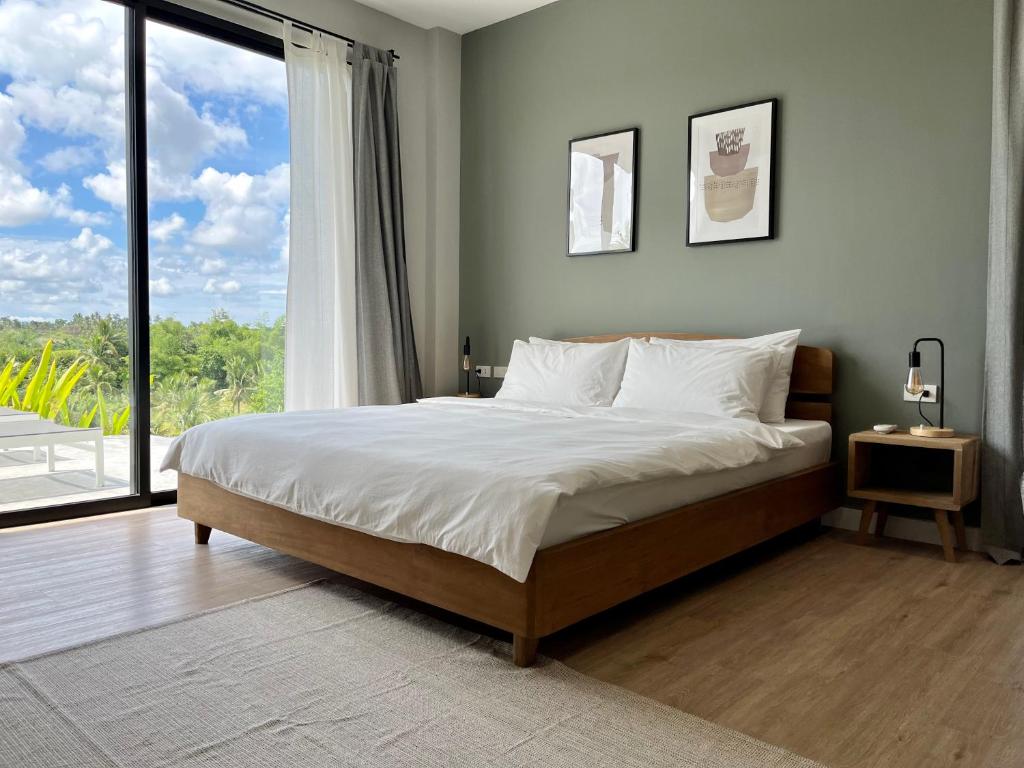 a bedroom with a large bed and a large window at La Résidence - Siargao in General Luna